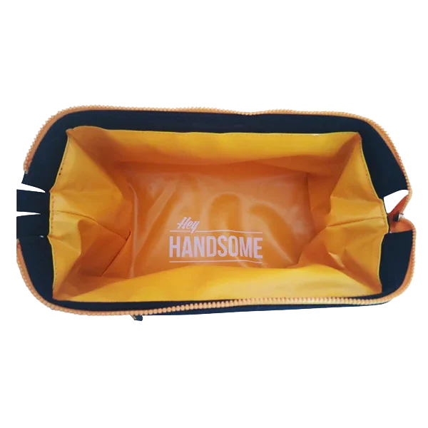 Open orange toiletry bag with 'Hey Handsome' text inside, view from above