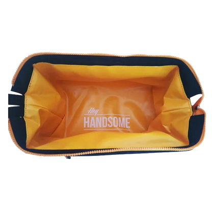 Open orange toiletry bag with 'Hey Handsome' text inside, view from above